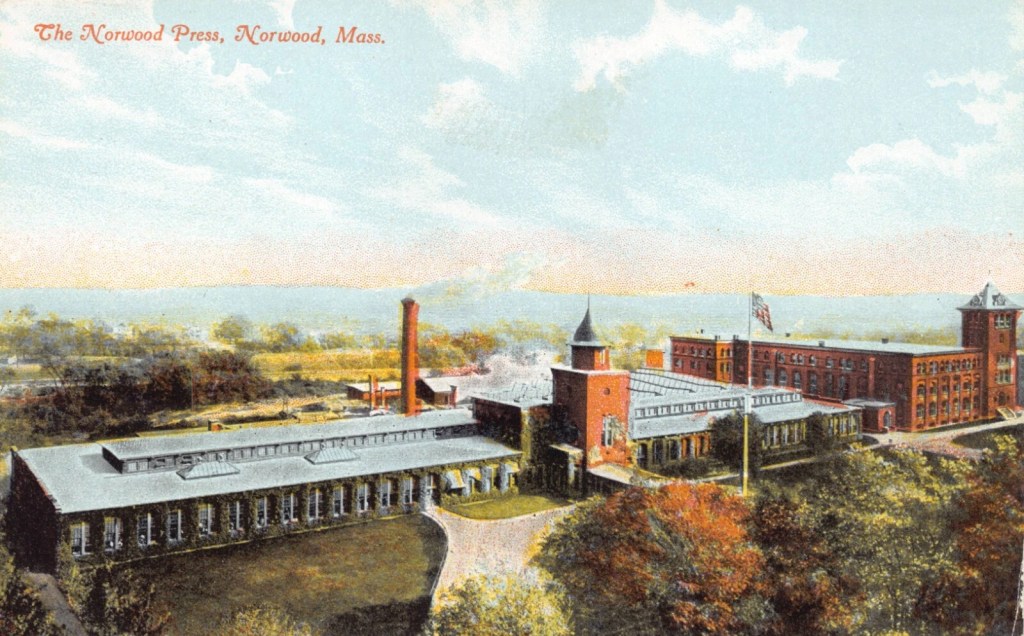 Aerial view of the Norwood Press building in Norwood, Massachusetts, showcasing its red brick architecture and surrounding landscape.