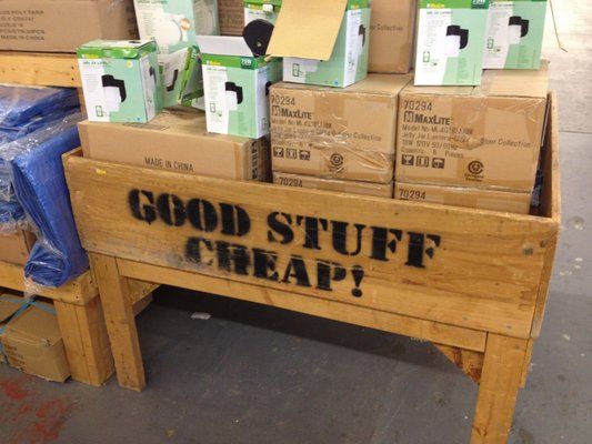 A wooden display featuring the phrase 'GOOD STUFF CHEAP!' surrounded by cardboard boxes and products.