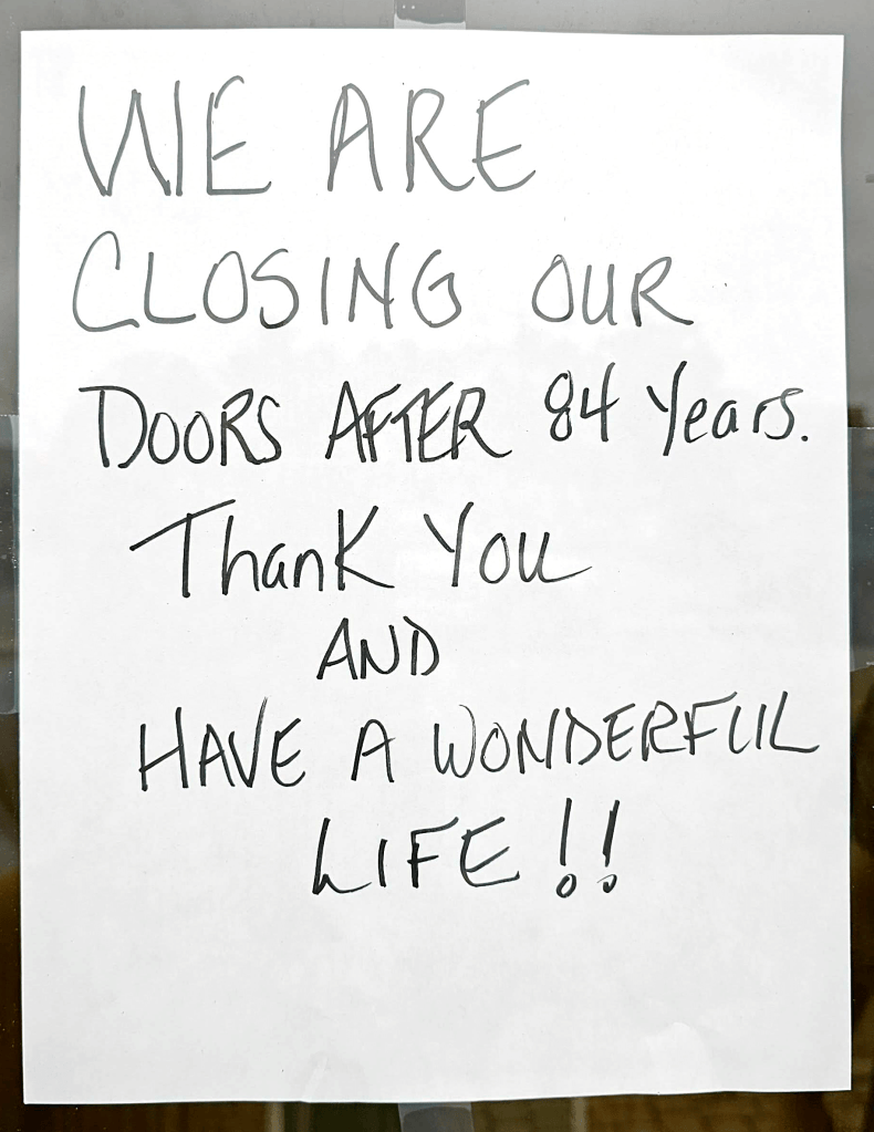 A handwritten sign announcing the closing of a business after 84 years, expressing gratitude and wishing customers a wonderful life.
