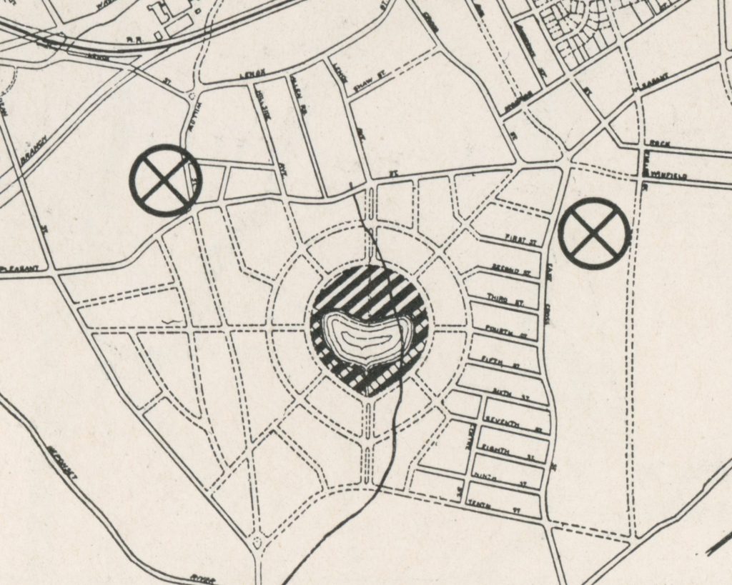 Black and white map showing a circular layout with streets and landmarks, featuring two circled symbols and patterns at the center.