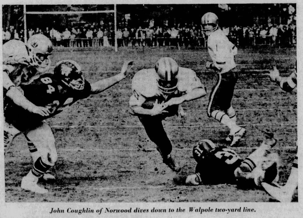 A football player diving towards the end zone while being tackled by defenders during a game.